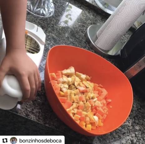 A importância de levar a criança para cozinha para preparar coisas simples como uma salada de fruta com um cortador seguro.